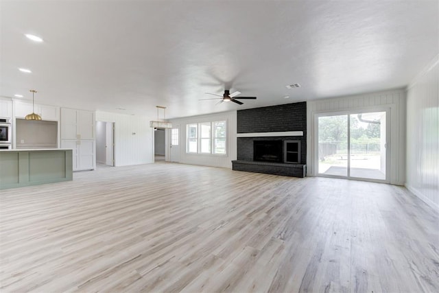 unfurnished living room featuring ceiling fan, light wood-type flooring, and a fireplace