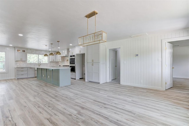 kitchen featuring a center island, light hardwood / wood-style flooring, gray cabinets, double oven, and decorative light fixtures