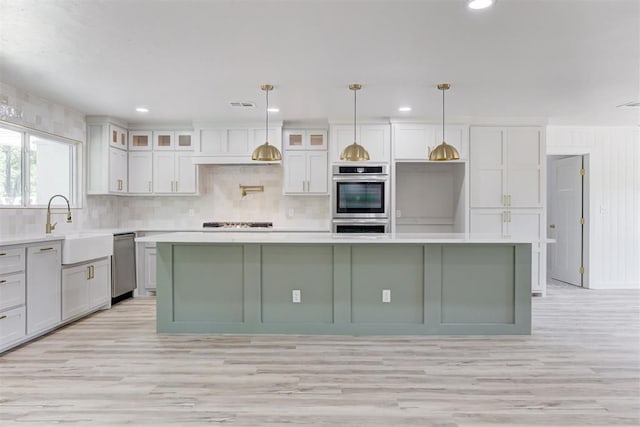 kitchen featuring a kitchen island, light hardwood / wood-style floors, hanging light fixtures, and stainless steel appliances