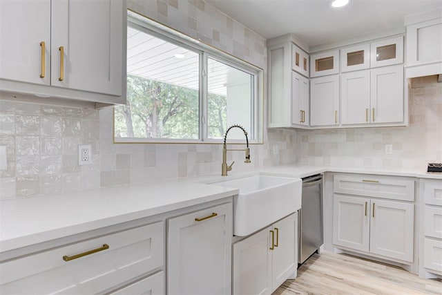 kitchen with decorative backsplash, white cabinetry, dishwasher, and sink