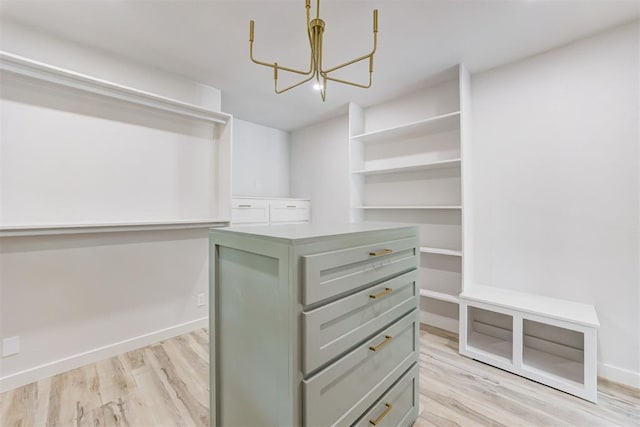 walk in closet featuring light wood-type flooring and an inviting chandelier