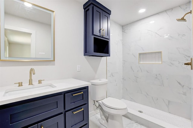 bathroom featuring a tile shower, vanity, and toilet