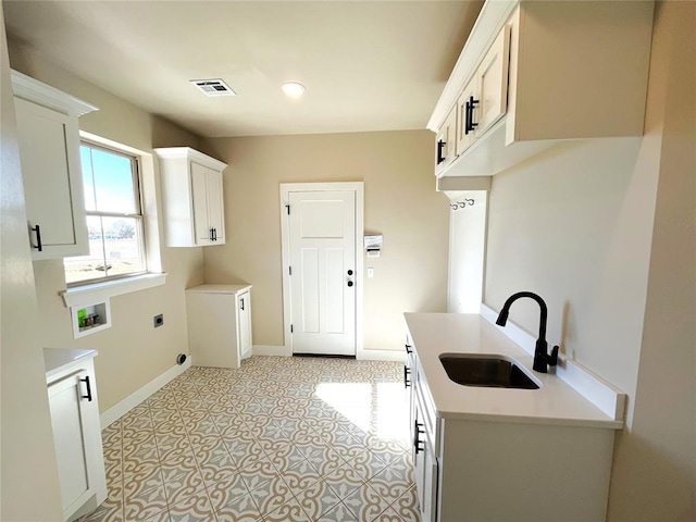 clothes washing area featuring cabinets, sink, washer hookup, light tile patterned floors, and hookup for an electric dryer