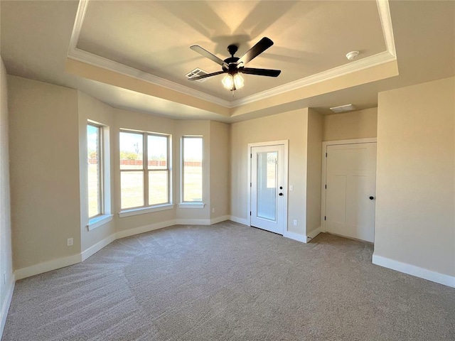 unfurnished room featuring a tray ceiling, ceiling fan, crown molding, and light colored carpet