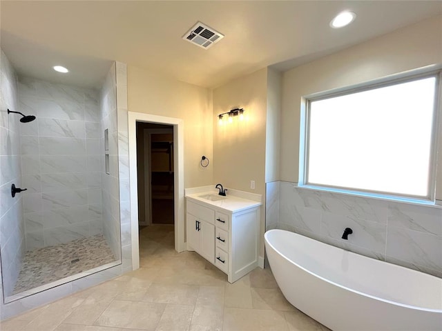 bathroom featuring tile patterned floors, plus walk in shower, vanity, and tile walls