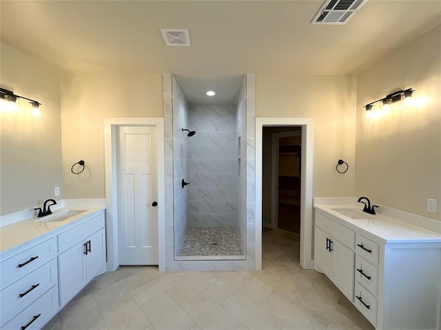 bathroom with tiled shower, vanity, and tile patterned flooring