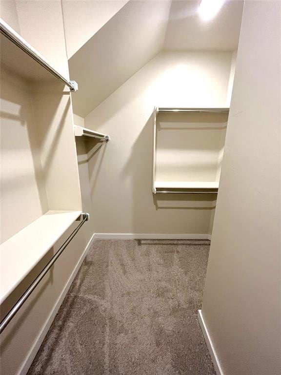 walk in closet with lofted ceiling and dark colored carpet