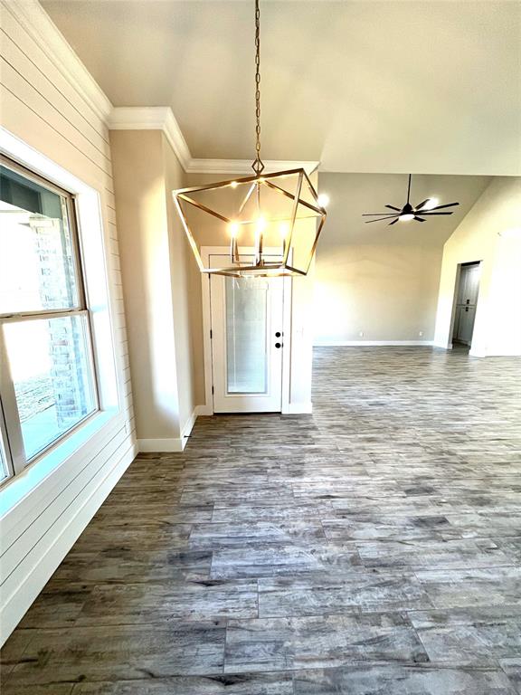 unfurnished dining area featuring lofted ceiling, ceiling fan with notable chandelier, hardwood / wood-style flooring, and ornamental molding