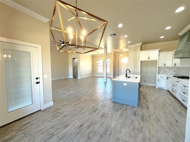 kitchen featuring sink, decorative light fixtures, a center island with sink, an inviting chandelier, and white cabinets