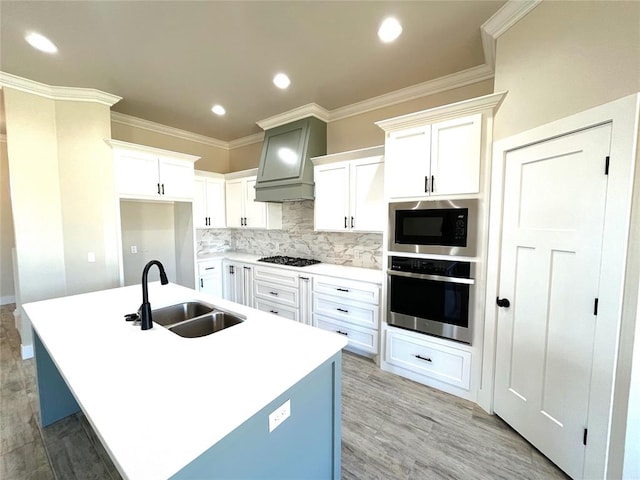 kitchen featuring built in microwave, a kitchen island with sink, stainless steel oven, and sink