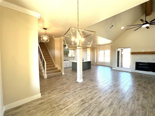 unfurnished living room featuring hardwood / wood-style floors, lofted ceiling with beams, ceiling fan with notable chandelier, and ornamental molding