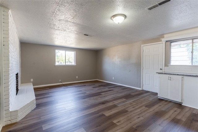 unfurnished living room with a fireplace, a textured ceiling, and dark wood-type flooring