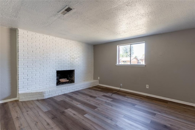 unfurnished living room featuring a fireplace, wood-type flooring, and a textured ceiling