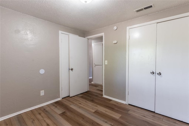 unfurnished bedroom featuring a textured ceiling, hardwood / wood-style flooring, and a closet