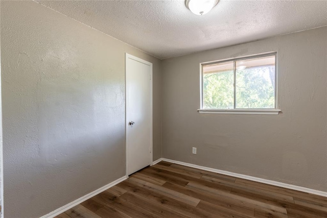 unfurnished room featuring a textured ceiling and dark wood-type flooring