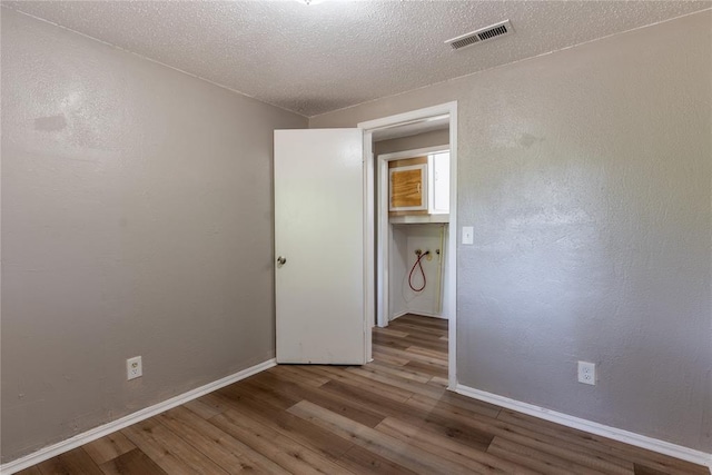 empty room with hardwood / wood-style floors and a textured ceiling