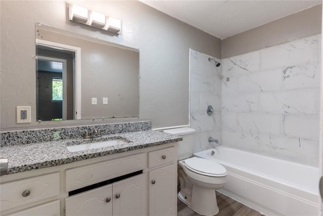 full bathroom with tiled shower / bath combo, hardwood / wood-style floors, a textured ceiling, toilet, and vanity