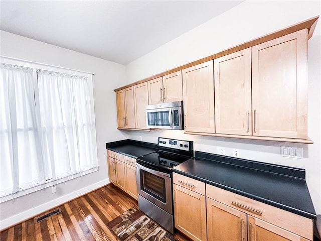 kitchen with dark hardwood / wood-style flooring, light brown cabinetry, and appliances with stainless steel finishes