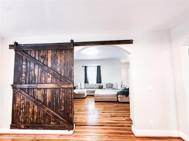 living room with a barn door and wood-type flooring