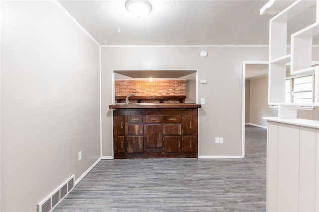 unfurnished living room with sink, wood-type flooring, and ornamental molding