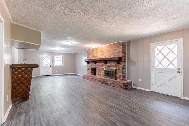 unfurnished living room featuring a textured ceiling, dark hardwood / wood-style floors, and a brick fireplace