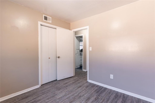 unfurnished bedroom featuring dark hardwood / wood-style flooring and a closet