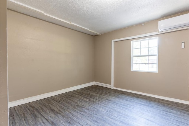 spare room featuring a textured ceiling, a wall mounted AC, and dark wood-type flooring