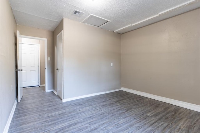 empty room featuring dark hardwood / wood-style flooring and a textured ceiling