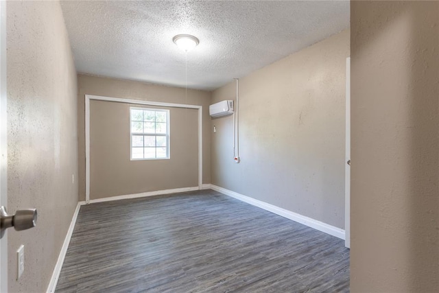 unfurnished room featuring dark hardwood / wood-style flooring, a textured ceiling, and a wall unit AC