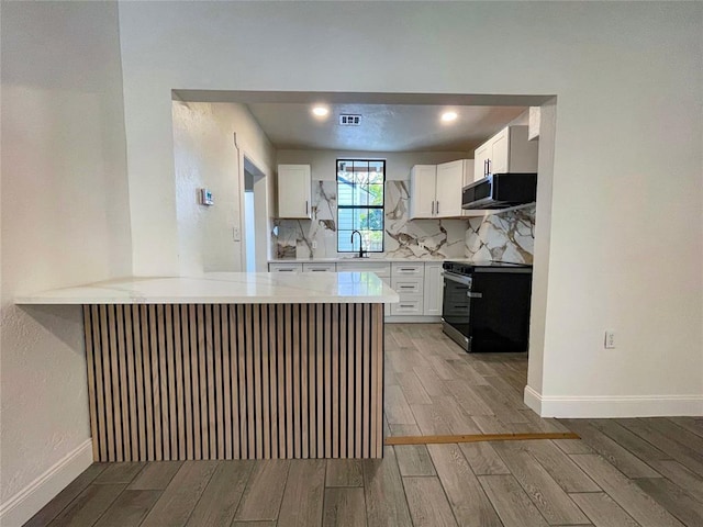 kitchen featuring decorative backsplash, kitchen peninsula, sink, electric stove, and white cabinetry