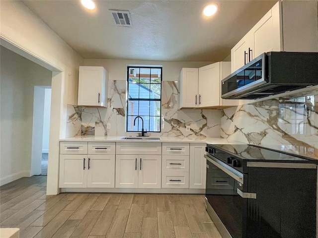 kitchen with light hardwood / wood-style floors, white cabinetry, sink, and black electric range