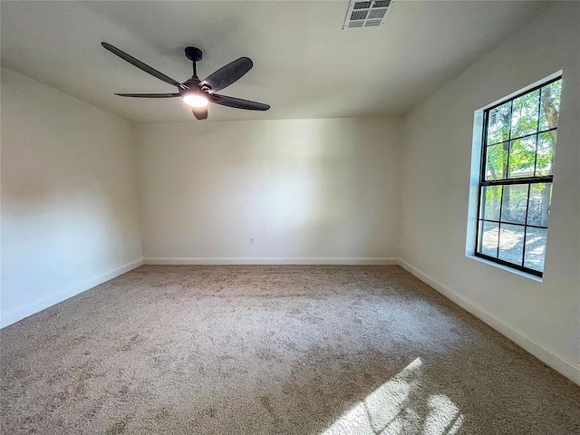 carpeted spare room featuring ceiling fan and a healthy amount of sunlight