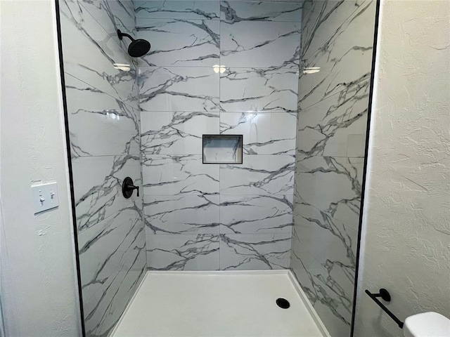 bathroom featuring tiled shower and toilet