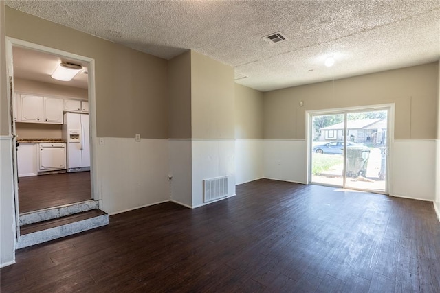 spare room featuring dark hardwood / wood-style flooring and a textured ceiling