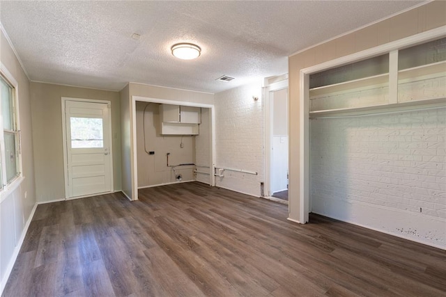 interior space featuring a closet, dark hardwood / wood-style flooring, brick wall, and a textured ceiling