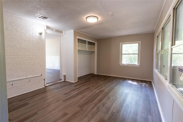 unfurnished bedroom featuring dark hardwood / wood-style floors, a textured ceiling, and a closet