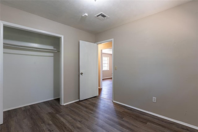 unfurnished bedroom featuring dark wood-type flooring and a closet