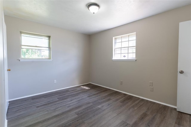 empty room featuring a healthy amount of sunlight and dark hardwood / wood-style flooring