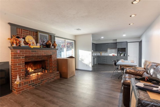 living room with dark hardwood / wood-style flooring, a textured ceiling, and a brick fireplace