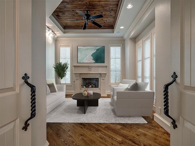 living room with wood ceiling, a tray ceiling, ceiling fan, crown molding, and hardwood / wood-style floors