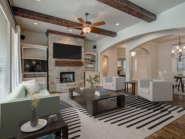 living room with ceiling fan with notable chandelier, beam ceiling, wood-type flooring, built in features, and a fireplace