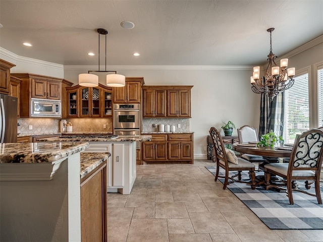 kitchen featuring pendant lighting, crown molding, light stone countertops, appliances with stainless steel finishes, and a chandelier