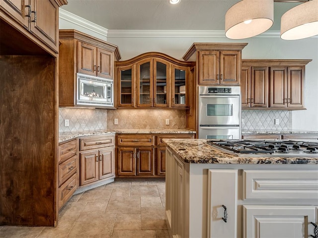 kitchen featuring tasteful backsplash, crown molding, light stone countertops, and appliances with stainless steel finishes