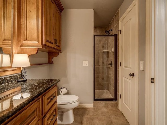 bathroom featuring tile patterned flooring, vanity, toilet, and a shower with door