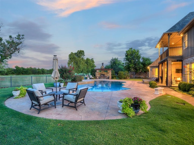 pool at dusk with a yard and a patio