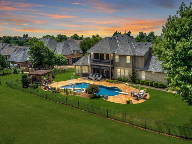 pool at dusk featuring outdoor lounge area, an in ground hot tub, a yard, and a patio