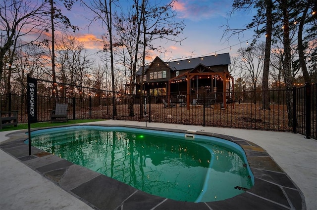 pool at dusk featuring a patio area and a gazebo