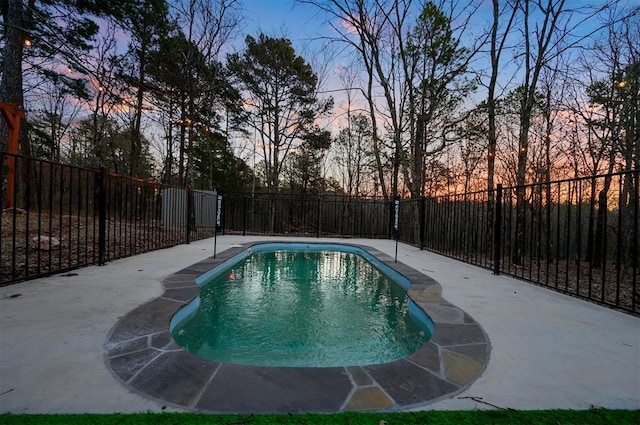 pool at dusk with a fenced backyard and a fenced in pool