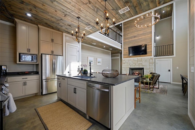 kitchen featuring finished concrete flooring, appliances with stainless steel finishes, a sink, and an island with sink