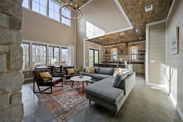 living area with a chandelier, concrete floors, wooden ceiling, and visible vents